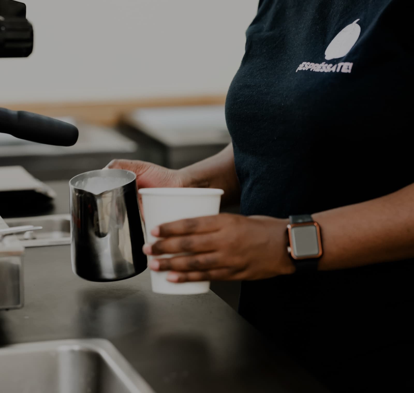 Espréssate barista in a branded shirt pouring steamed milk into a cup at a catered event in Durham